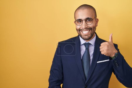 Photo for Hispanic man with beard wearing suit and tie doing happy thumbs up gesture with hand. approving expression looking at the camera showing success. - Royalty Free Image