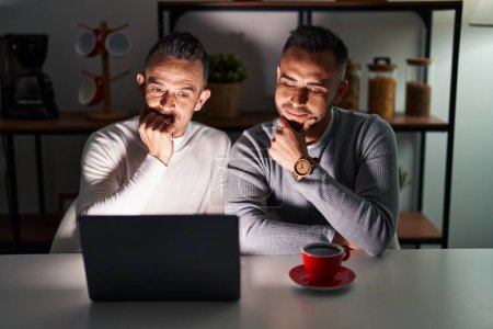 Photo for Homosexual couple using computer laptop looking confident at the camera smiling with crossed arms and hand raised on chin. thinking positive. - Royalty Free Image