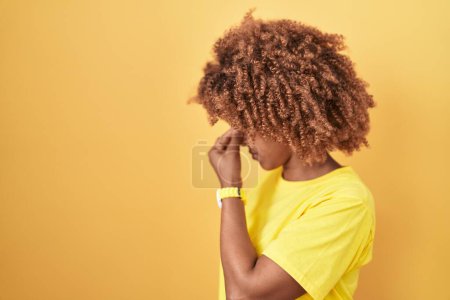 Foto de Mujer hispana joven con el pelo rizado de pie sobre fondo amarillo cansada frotando la nariz y los ojos sintiendo fatiga y dolor de cabeza. concepto de estrés y frustración. - Imagen libre de derechos