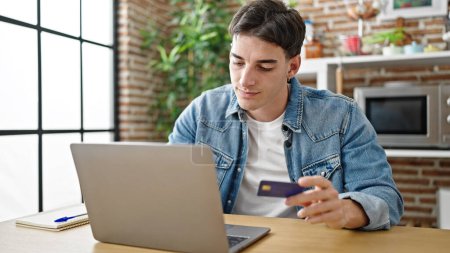 Photo for Young hispanic man shopping with laptop and credit card sitting on table at dinning room - Royalty Free Image