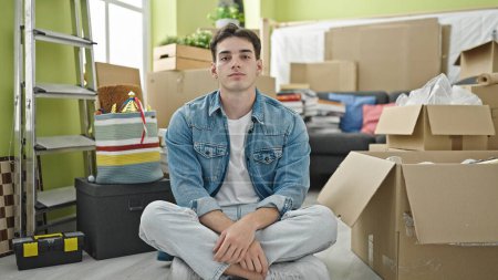 Photo for Young hispanic man sitting on floor with relaxed expression at new home - Royalty Free Image