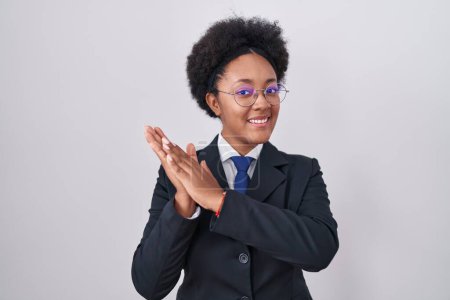 Téléchargez les photos : Belle femme africaine aux cheveux bouclés portant une veste d'affaires et des lunettes applaudissant et applaudissant heureux et joyeux, souriant mains fières ensemble - en image libre de droit