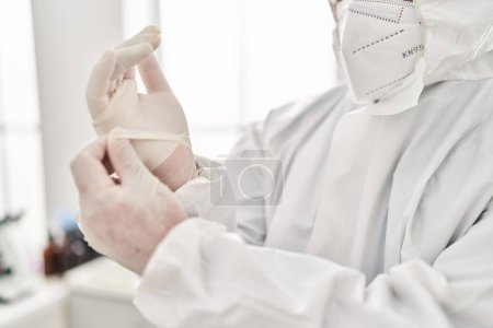 Photo for Young latin man scientist wearing covid protection uniform and gloves at laboratory - Royalty Free Image