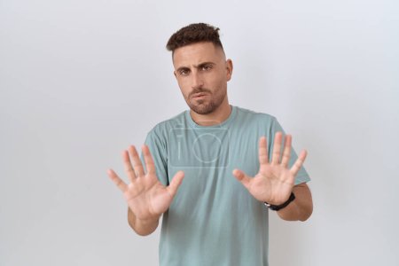 Photo for Hispanic man with beard standing over white background moving away hands palms showing refusal and denial with afraid and disgusting expression. stop and forbidden. - Royalty Free Image