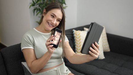 Photo for Young pregnant woman having video call showing baby ultrasound at home - Royalty Free Image