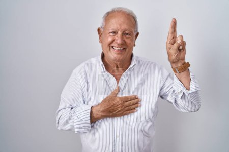 Téléchargez les photos : Homme âgé avec les cheveux gris debout sur fond isolé souriant jurant avec la main sur la poitrine et les doigts vers le haut, faisant un serment de fidélité promesse - en image libre de droit