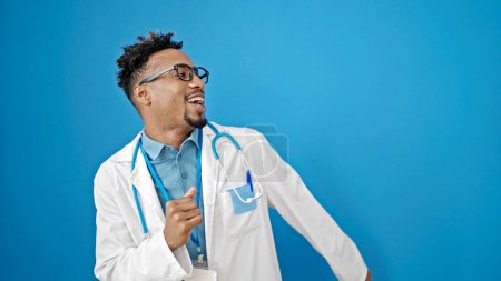 Photo for African american man doctor smiling confident dancing over isolated blue background - Royalty Free Image