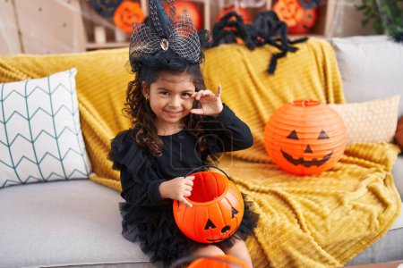 Téléchargez les photos : Adorable fille hispanique ayant fête d'Halloween faisant geste effrayant à la maison - en image libre de droit