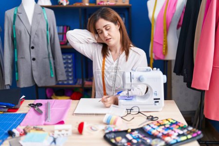 Foto de Mujer joven sastre estresado utilizando la máquina de coser en el estudio de costura - Imagen libre de derechos