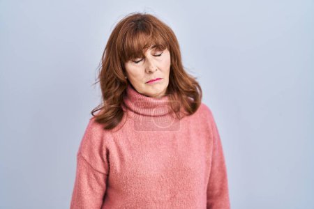 Foto de Middle age hispanic woman standing over isolated background looking sleepy and tired, exhausted for fatigue and hangover, lazy eyes in the morning. - Imagen libre de derechos