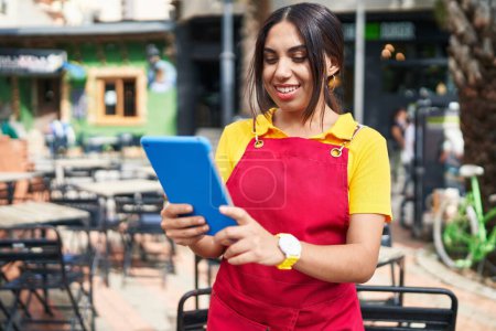 Foto de Young beautiful arab woman waitress smiling confident using touchpad at coffee shop terrace - Imagen libre de derechos