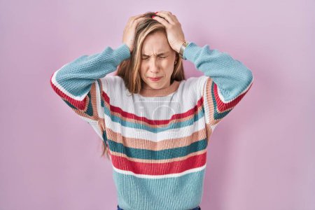 Photo for Young blonde woman standing over pink background suffering from headache desperate and stressed because pain and migraine. hands on head. - Royalty Free Image