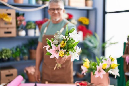 Photo for Middle age grey-haired man florist holding bouquet of flowers at flower shop - Royalty Free Image