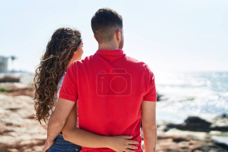 Foto de Joven pareja hispana turistas abrazándose de pie en la orilla del mar - Imagen libre de derechos