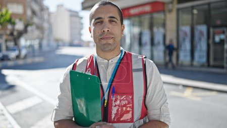 Téléchargez les photos : Jeune homme hispanique bénévole tenant presse-papiers à la rue - en image libre de droit