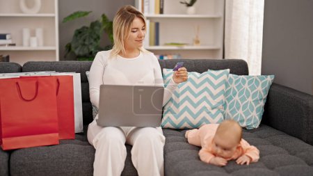 Téléchargez les photos : Achats mère et fille avec ordinateur portable et carte de crédit assis ensemble à la maison - en image libre de droit