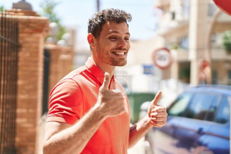 Téléchargez les photos : Young hispanic man smiling confident doing ok sign with thumbs up at street - en image libre de droit