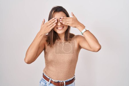 Photo for Young hispanic woman standing over white background covering eyes with hands smiling cheerful and funny. blind concept. - Royalty Free Image