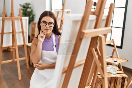 Photo for Young beautiful hispanic woman artist smiling confident talking on smartphone at art studio - Royalty Free Image