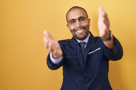 Photo for Hispanic man with beard wearing suit and tie looking at the camera smiling with open arms for hug. cheerful expression embracing happiness. - Royalty Free Image