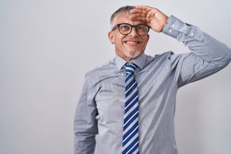 Foto de Hombre de negocios hispano con el pelo gris usando gafas sonriente seguro de tocar el cabello con la mano hacia arriba gesto, posando atractivo y de moda - Imagen libre de derechos