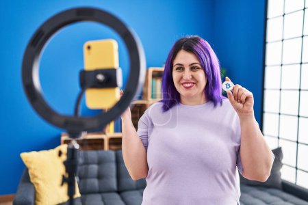 Foto de Tamaño más mujer ingenio púrpura grabación de pelo bitcoin tutorial con smartphone en casa gritando orgulloso, celebrando la victoria y el éxito muy emocionado con el brazo levantado - Imagen libre de derechos