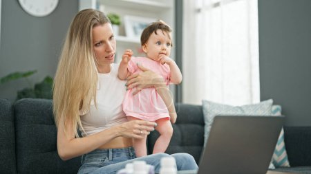 Téléchargez les photos : Mère et fille utilisant un ordinateur portable ayant une consultation pédiatre en ligne à la maison - en image libre de droit
