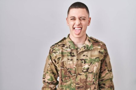 Photo for Young man wearing camouflage army uniform sticking tongue out happy with funny expression. emotion concept. - Royalty Free Image