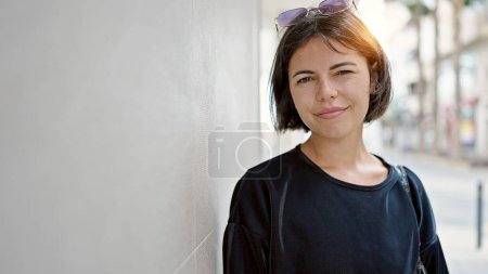 Téléchargez les photos : Jeune belle femme hispanique debout avec une expression sérieuse dans la rue - en image libre de droit