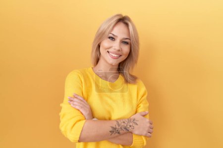 Photo for Young caucasian woman wearing yellow sweater happy face smiling with crossed arms looking at the camera. positive person. - Royalty Free Image