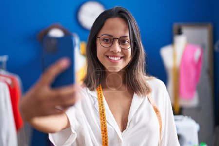 Téléchargez les photos : Jeune femme hispanique tailleur faire selfie par smartphone au studio de couture - en image libre de droit