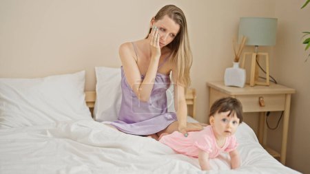 Photo for Mother and daughter sitting on bed with sad expression at bedroom - Royalty Free Image