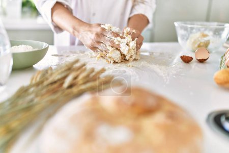 Photo for Young woman wearing cook uniform kneading flour at kitchen - Royalty Free Image