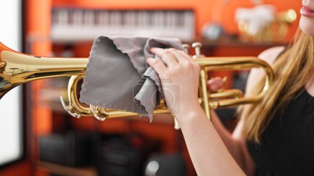 Téléchargez les photos : Jeune femme blonde musicienne nettoyage trompette au studio de musique - en image libre de droit