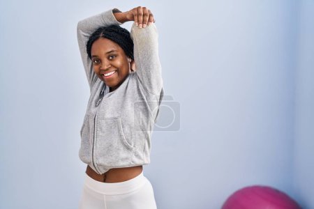 Photo for African american woman smiling confident stretching arm at sport center - Royalty Free Image