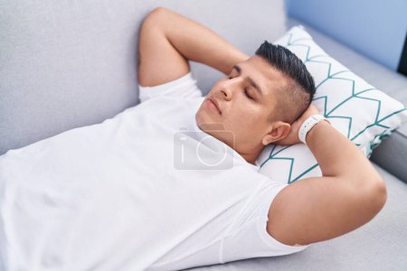 Téléchargez les photos : Jeune homme latino couché sur le canapé dormant à la maison - en image libre de droit