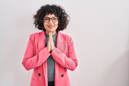 Photo for Hispanic woman with curly hair standing over isolated background praying with hands together asking for forgiveness smiling confident. - Royalty Free Image