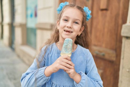 Téléchargez les photos : Adorable fille caucasienne souriant confiance manger de la crème glacée à la rue - en image libre de droit