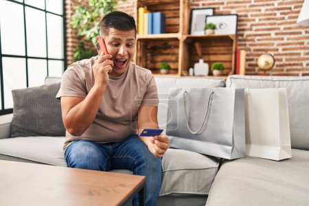 Photo for Hispanic young man doing payment with credit card on the phone celebrating crazy and amazed for success with open eyes screaming excited. - Royalty Free Image