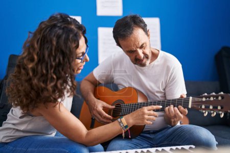 Foto de Man and woman musicians having classical guitar lesson at music studio - Imagen libre de derechos