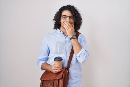 Téléchargez les photos : Homme hispanique avec les cheveux bouclés boire une tasse de café à emporter rire et rire embarrassé couvrant la bouche avec les mains, commérages et concept scandale - en image libre de droit