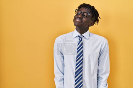 Téléchargez les photos : Homme africain avec dreadlocks debout sur fond jaune souriant regardant vers le côté et regardant loin en pensant. - en image libre de droit