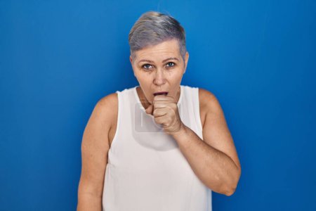 Photo for Middle age caucasian woman standing over blue background feeling unwell and coughing as symptom for cold or bronchitis. health care concept. - Royalty Free Image