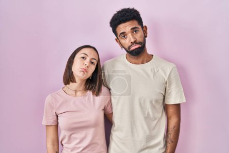 Photo for Young hispanic couple together over pink background depressed and worry for distress, crying angry and afraid. sad expression. - Royalty Free Image