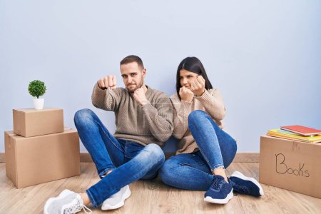 Photo for Young couple moving to a new home ready to fight with fist defense gesture, angry and upset face, afraid of problem - Royalty Free Image