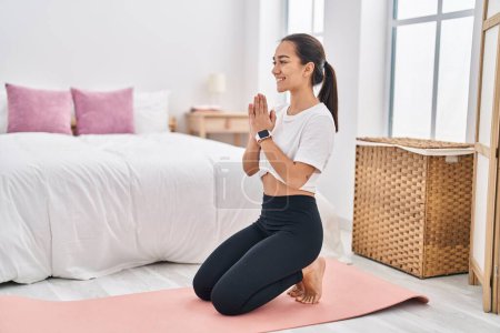 Téléchargez les photos : Jeune femme hispanique souriant yoga d'entraînement confiant à la chambre - en image libre de droit