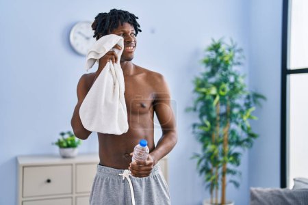 Téléchargez les photos : Athlète afro-américain tenant de l'eau et une serviette à la maison - en image libre de droit