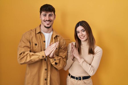 Téléchargez les photos : Jeune couple hispanique debout sur fond jaune applaudissant et applaudissant heureux et joyeux, souriant mains fiers ensemble - en image libre de droit