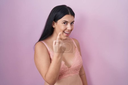 Téléchargez les photos : Jeune femme hispanique portant un soutien-gorge rose signe venir ici geste avec la main invitant accueillant heureux et souriant - en image libre de droit