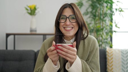 Téléchargez les photos : Jeune belle femme hispanique avec mousse café sur les lèvres à la maison - en image libre de droit